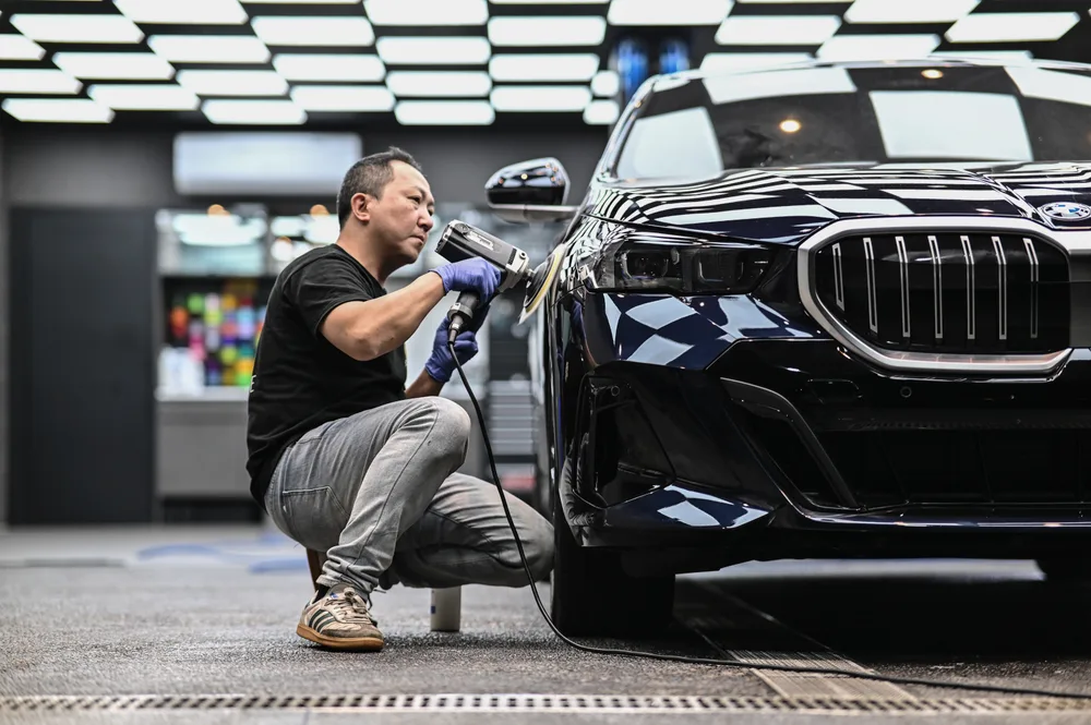 技師蹲姿手持拋光機研磨 BMW 前葉子板,全車已完成前置清潔