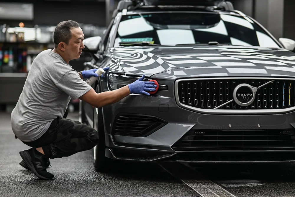 技師蹲在車頭前,逐處清潔水箱罩與前保桿