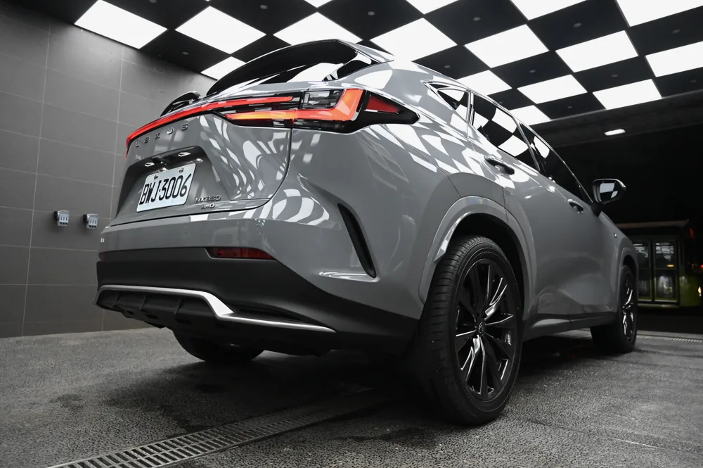 Lexus NX 350 車尾四分之三視角,貫穿式尾燈與後保桿線條在廠內燈光下反射清晰