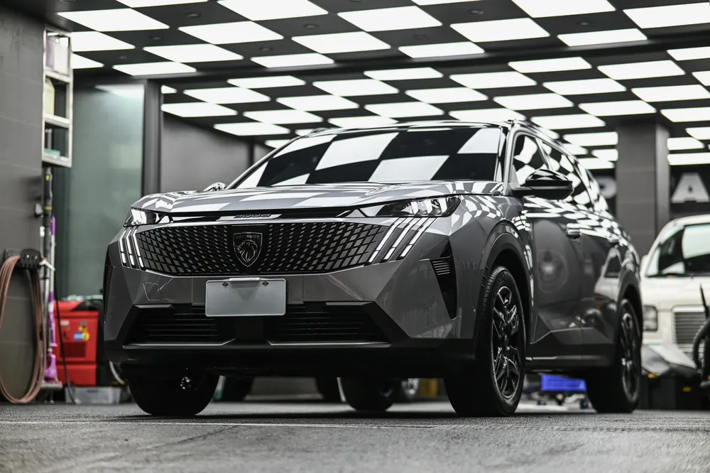 銀灰色 Peugeot 5008 停在施工棚內,車頭正面在黑白格燈光下的整體視角